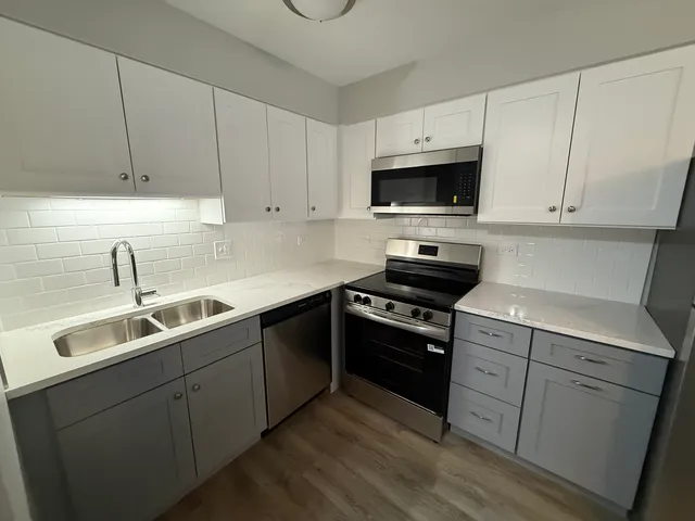 a kitchen with cabinets stainless steel appliances a sink and a stove