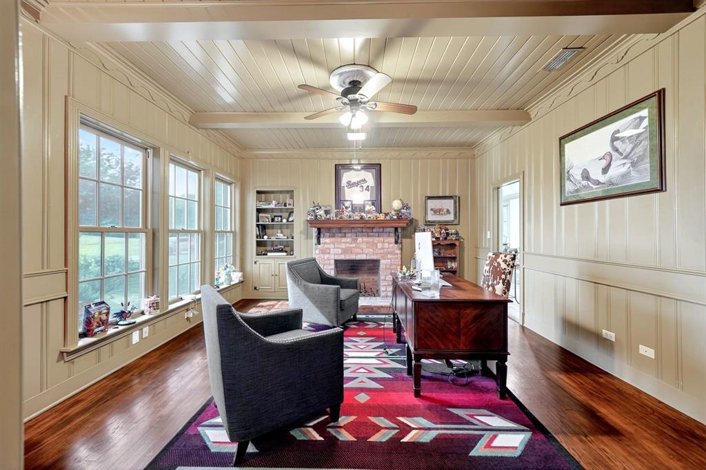 1901 Rose Pointe Athens, TX 75752 - Photo 6 of 37 Room featuring wood-finish flooring, a brick fireplace, built-in shelving, paneled walls, and multiple grid-pattern windows