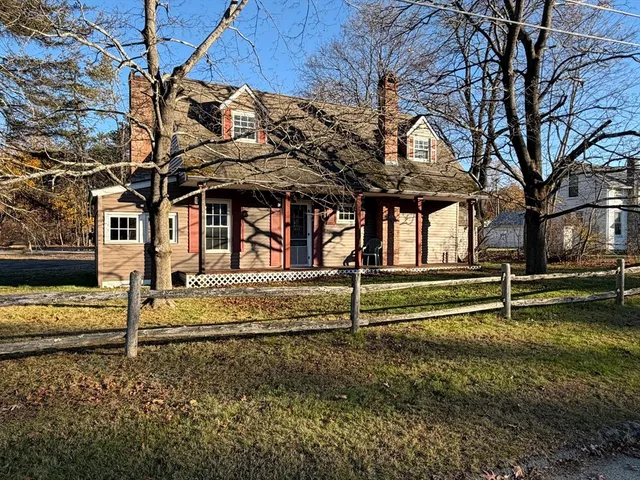 a view of a house with a large tree and wooden fence