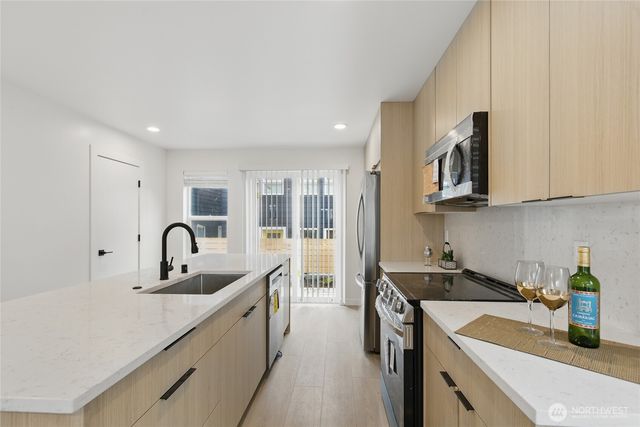 a kitchen with stainless steel appliances granite countertop a sink a stove and a refrigerator