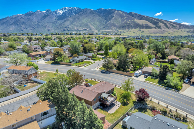 12080 Mill Ridge Circle Sandy, UT 84094 - Photo 42 of 56 Aerial perspective showcasing a residential area with varied housing styles and mature landscaping, set against a backdrop of snow-capped mountains