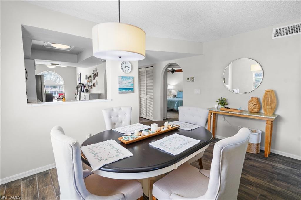 601 Augusta Boulevard, Unit 10 Naples, FL 34113 - Photo 7 of 27 Dining room featuring dark wood finished floors, ceiling fan, arched walkways, and a textured ceiling