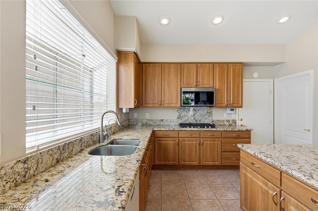 9034 Ridgepointe Way Henderson, NV 89074 - Photo 21 of 56 Gleaming granite countertops pair beautifully with warm wood cabinetry and neutral tile flooring.