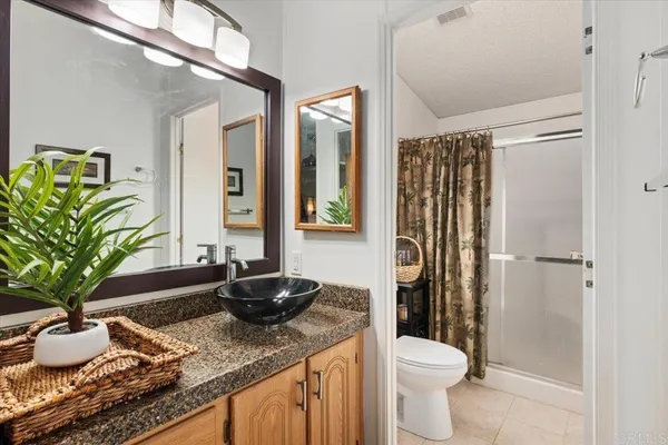 a bathroom with a granite countertop sink a toilet a mirror and shower