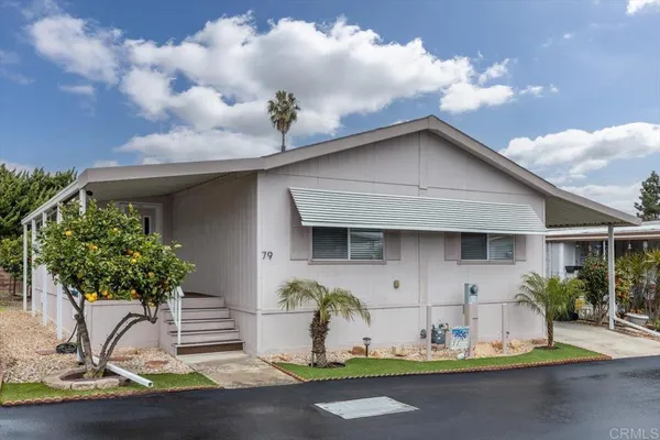 a white house with a yard plants and palm trees