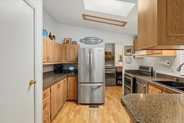 a kitchen with stainless steel appliances granite countertop a refrigerator a stove and a wooden floors