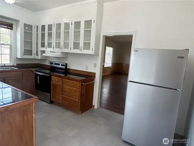 a kitchen with a refrigerator a stove top oven and cabinets