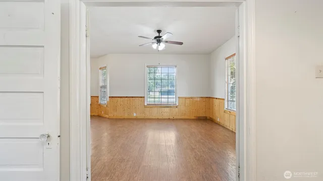 a view of an empty room with a window and wooden floor