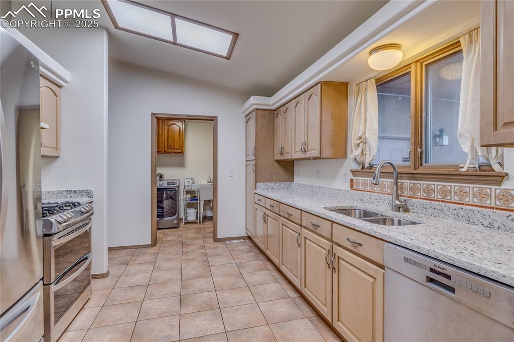 7501 Tudor Road Colorado Springs, CO 80919 - Photo 13 of 48 Kitchen with tile floors/new granite counter tops - straight ahead is the laundry room and door to the 3 car garage.
