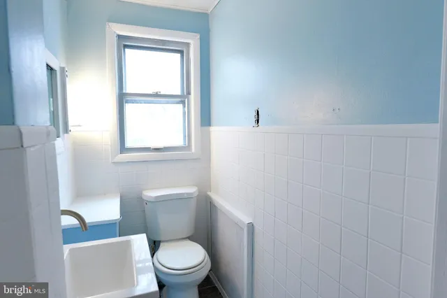 a white toilet sitting next to a bathroom sink and a window