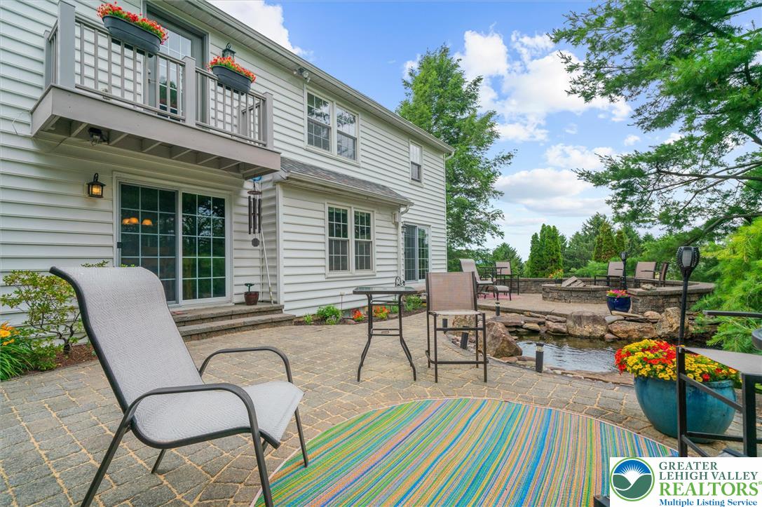5616 Snowdrift Road Orefield, PA 18069 - Photo 31 of 36 An inviting stone patio unfolds with a private pond and a second-story balcony overlooking the verdant landscape.