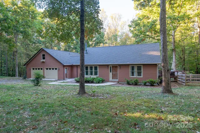 a view of a house with a yard and large trees