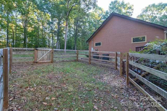 a view of a backyard with wooden fence and large trees
