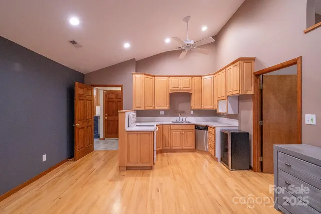 a large kitchen with a large counter top a sink stainless steel appliances and cabinets