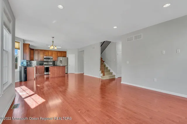 a kitchen with stainless steel appliances granite countertop a stove top oven a refrigerator a sink and dishwasher with wooden floor