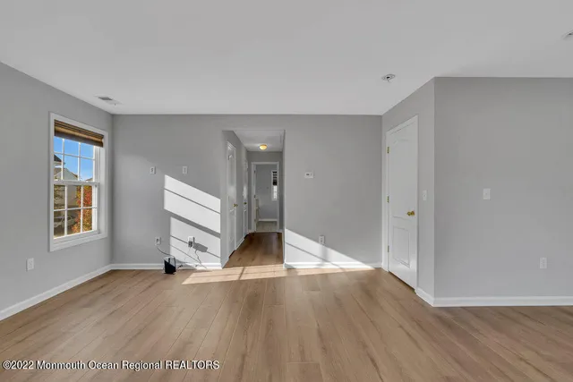 a view of empty room with window and wooden floor