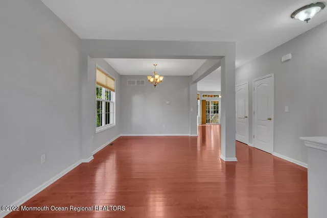 a view of an empty room with window and wooden floor