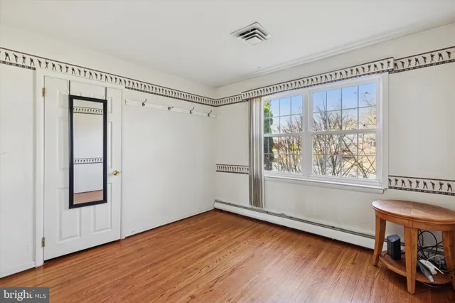 a view of an empty room with a window and wooden floor