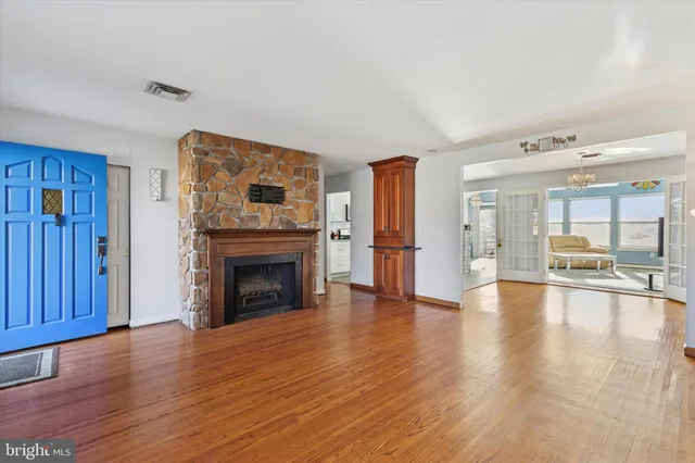 a view of an empty room with wooden floor fireplace and a window
