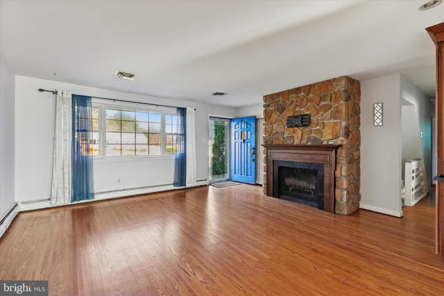 an empty room with wooden floor fireplace and windows