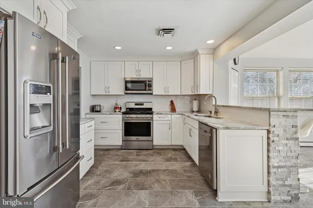 a kitchen with stainless steel appliances granite countertop a refrigerator sink and stove