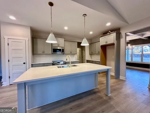 a large kitchen with stainless steel appliances granite countertop a sink a stove and a wooden floors