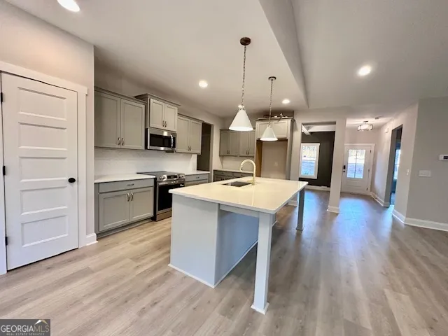 a large kitchen with a center island wooden floor stainless steel appliances and cabinets