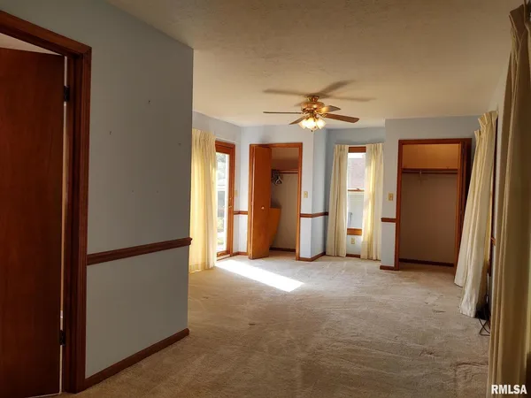 an empty room with closet and a hallway