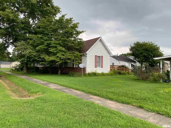 a view of a house with a big yard potted plants and large tree