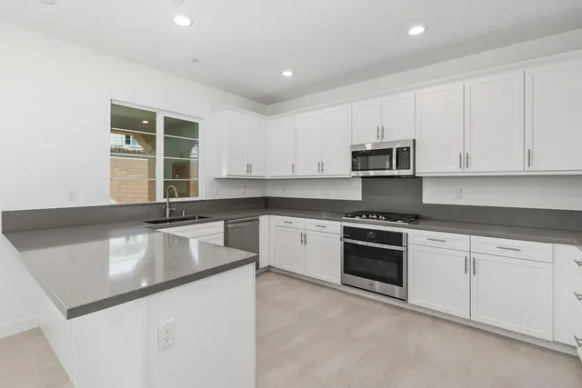 a kitchen with granite countertop white cabinets and stainless steel appliances