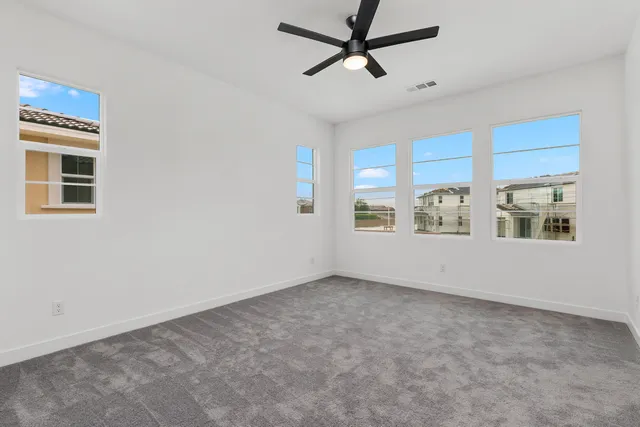 a view of empty room with window and ceiling fan