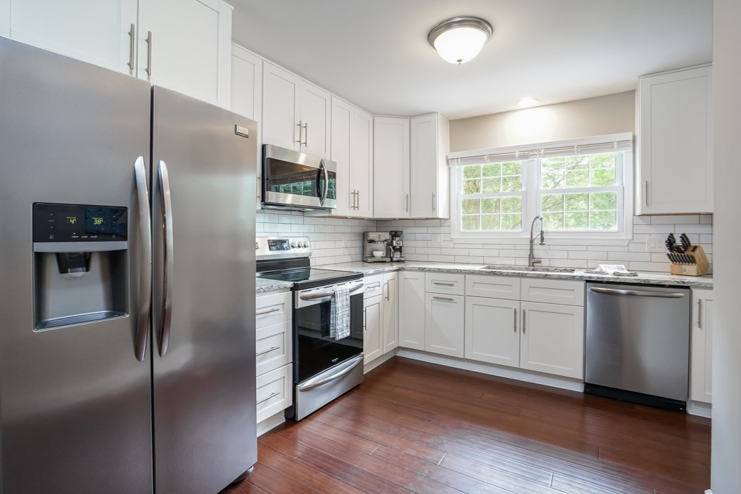 1318 Springlawn Court Raleigh, NC 27609 - Photo 9 of 30 42" white shaker cabinets with European style satin nickel pulls. Granite counters and subway tile backsplash.