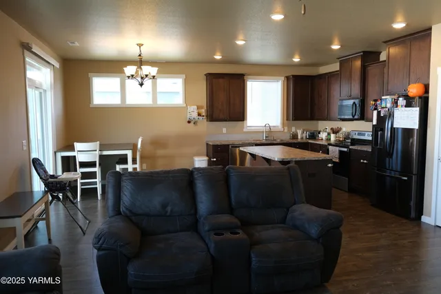 a living room with stainless steel appliances kitchen island granite countertop furniture a refrigerator a sink a dining table and chairs