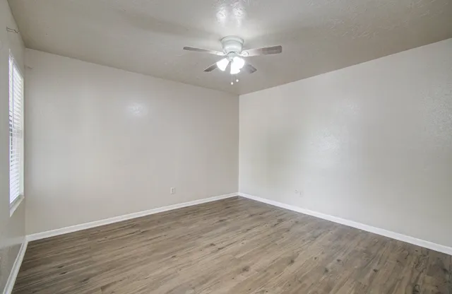 a view of a room with wooden floor and a ceiling fan