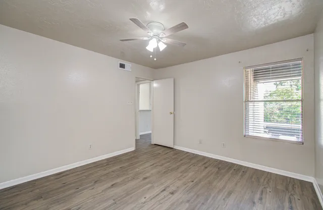 an empty room with wooden floor and windows