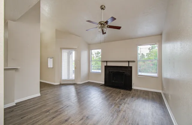 a view of an empty room with wooden floor fireplace and a window