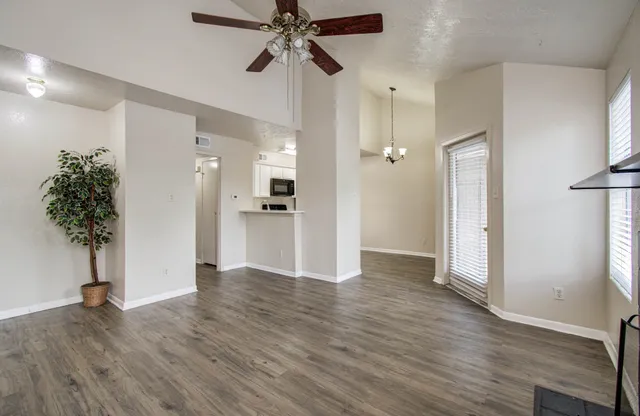a view of a hallway with wooden floor and a ceiling fan