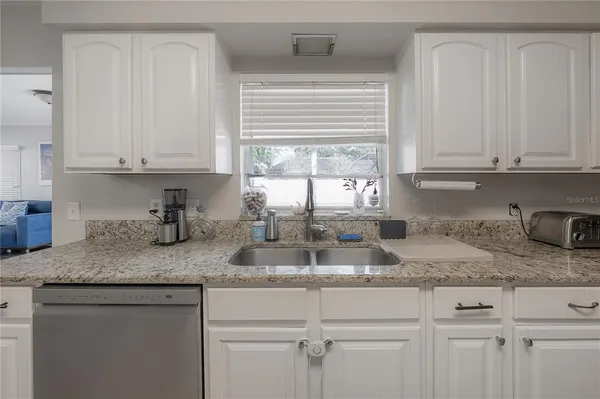 a kitchen with granite countertop white cabinets white appliances and a counter space