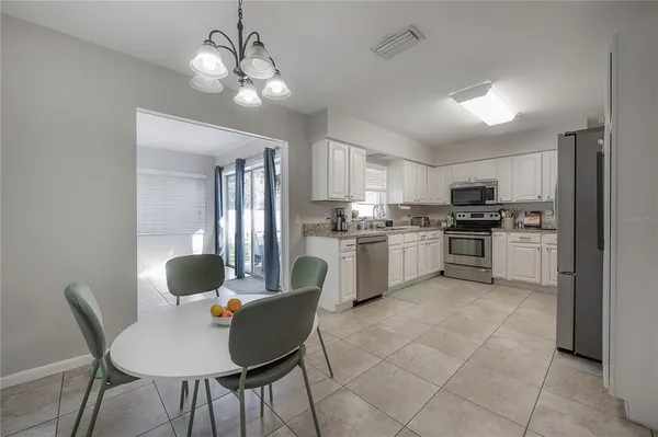 a kitchen with stainless steel appliances granite countertop a stove top oven a sink dishwasher a dining table and chairs with wooden floor