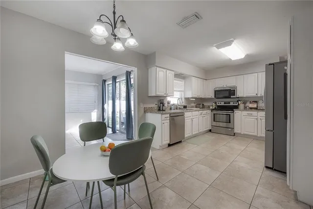 a kitchen with stainless steel appliances granite countertop a stove top oven a sink dishwasher a dining table and chairs with wooden floor