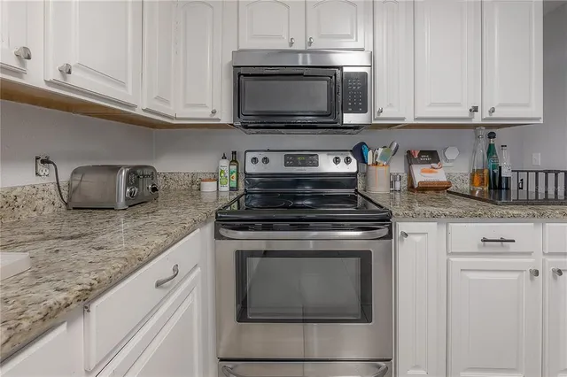 a kitchen with granite countertop white cabinets and a stove top oven