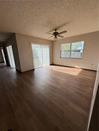 a view of an empty room with a window and wooden floor