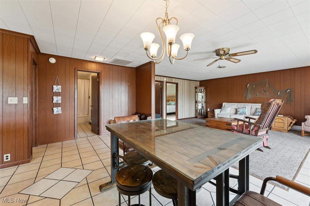 86413 North Bay Road Scio, OH 43988 - Photo 16 of 45 Dining room with light tile patterned floors, ceiling fan with notable chandelier, and wooden walls