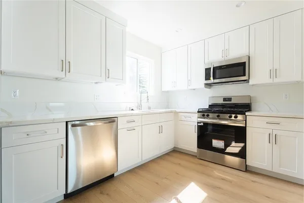 a kitchen with granite countertop white cabinets and stainless steel appliances