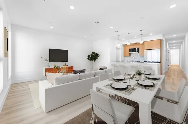 a living room with furniture a flat screen tv and kitchen view