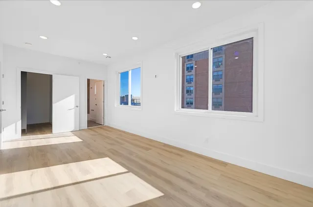 a view of an empty room with wooden floor and windows