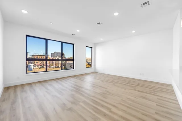 a view of an empty room with a window and wooden floor