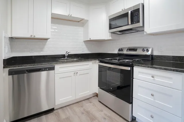 a kitchen with stainless steel appliances granite countertop grey cabinets a stove a sink and dishwasher