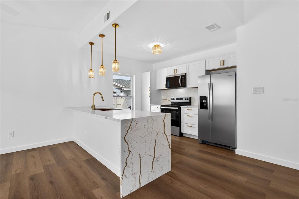 662 Bryan Terrace Drive Brandon, FL 33511 - Photo 7 of 30 a kitchen with kitchen island a sink stainless steel appliances and wooden floor