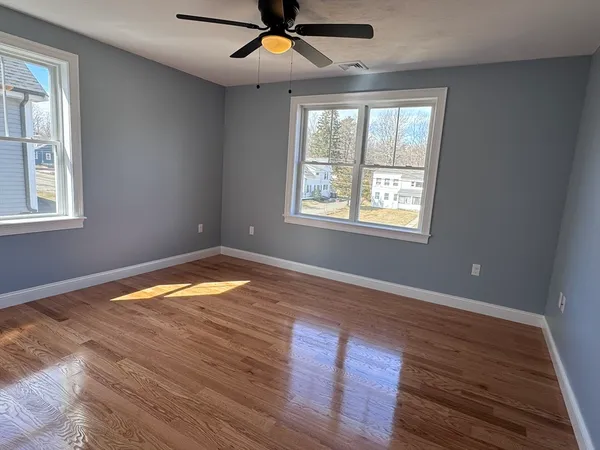 a view of empty room with wooden floor and fan